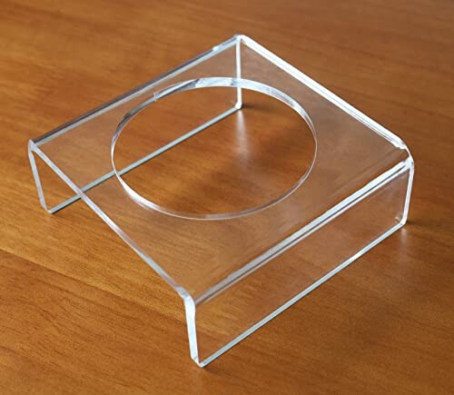 Clear acrylic display stand with circular cutout on wooden surface.