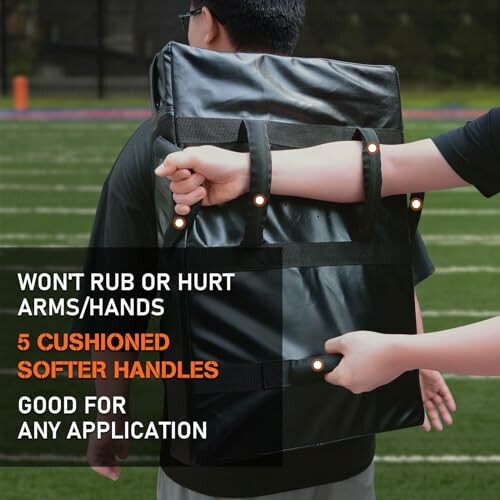 Person carrying a backpack with cushioned handles on a sports field.