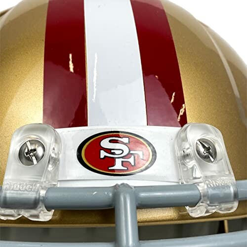 Close-up of a football helmet with gold and red stripes and an SF logo.