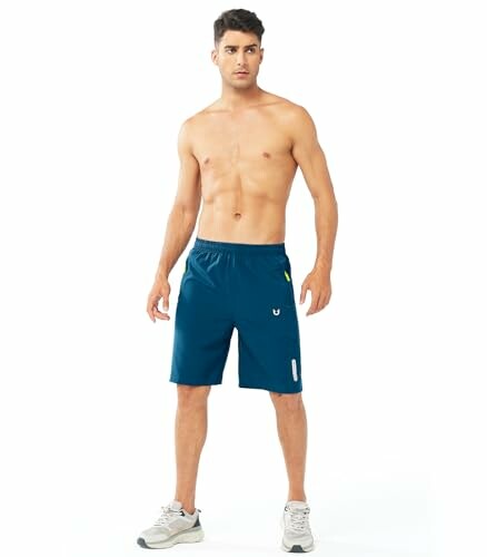 Man wearing blue shorts and sneakers, standing against a white background.