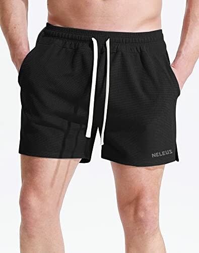Man wearing black athletic shorts with drawstring.