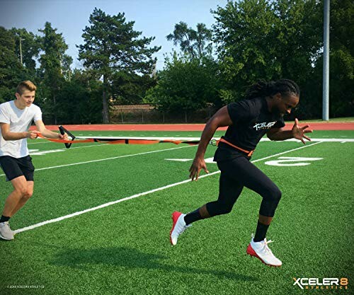 Two athletes performing resistance training on a track with a band.