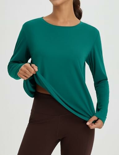 Woman wearing a green long-sleeve shirt and brown leggings.